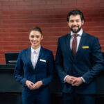 hotel receptionists standing together in front of counter and looking at camera